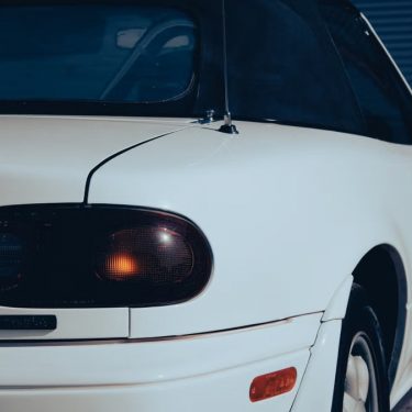 Detailed view of a classic white sports car rear in daylight, showcasing its vintage design.